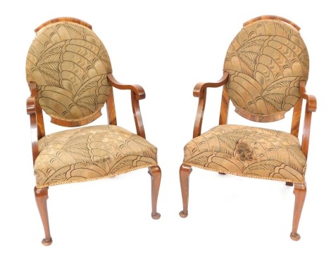 A pair of walnut Art Deco dining chairs, each with an oval back on cabriole legs, with wave design tapestry cushions, 92cm high, 60cm wide.