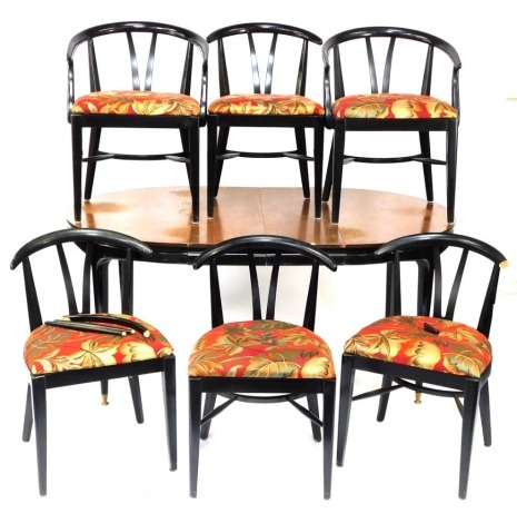 A walnut and ebonised dining suite, comprising a circular extending table, with ebonised supports on tapered feet terminating in brass castors, 76cm high, 111cm diameter, together with a set of six chairs, each in similar style, newly upholstered red cove