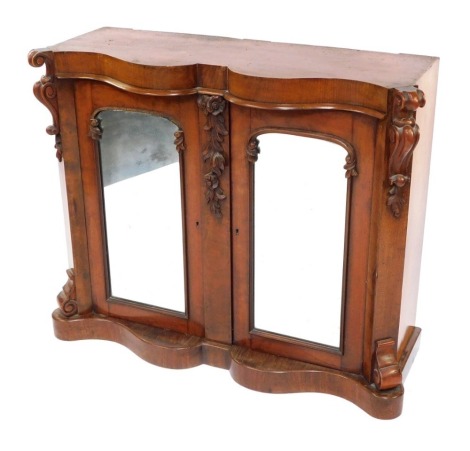 A Victorian mahogany sideboard, with curved and moulded top with raised scroll supports and leaf and vine flowers, with two mirrored back doors, lacking top, 88cm high, 101cm wide, 35cm deep.