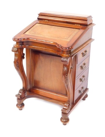 A hardwood Davenport, with a raised ink well top, and fall flap with tan leather insert, opening to reveal a fitted interior, on scroll front with single door, arrangement of four drawers on bun feet terminating in castors, 90cm high, 56cm wide, 56cm deep