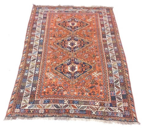 A Persian rug, with three medallion centre on orange and blue ground, with tassel ends, 186cm x 137cm.