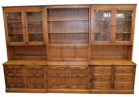 An Ercol dining room suite, comprising three cupboard section including a pair of cupboard glazed tops with two shelves, open shelf section with two cupboard base, on block feet with carved detail, 180cm high, 97cm wide, 50cm deep, and a middle section wi