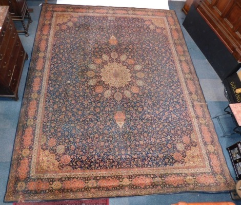 A Middle Eastern rug, on a blue and red ground, with central flower medallion, flowers and vases, on a material backing, 410cm x 318cm.