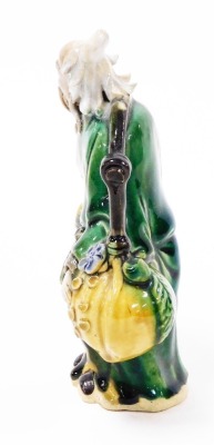 A Chinese pottery figure of a sage, carrying yoke bearing a coin and a flowering peach, 15cm high, and two porcelain figural snuff bottles, 9cm and 8cm high. - 9