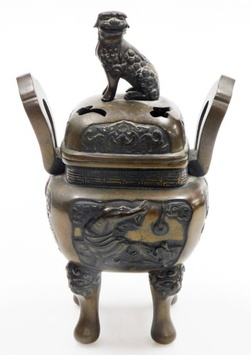 A Chinese bronze koro and cover, on four feet, the body decorated with four reserves depicting figures and animal, the pierced lid with dog of fo finial, 25cm high.