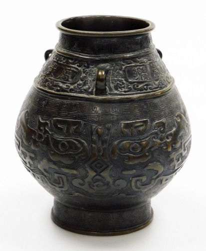 A bulbous Chinese bronze vase, on flared foot, the body cast with archaistic reliefs of animals below lug handles and frieze with inscription, the base with six character mark, 19cm high.