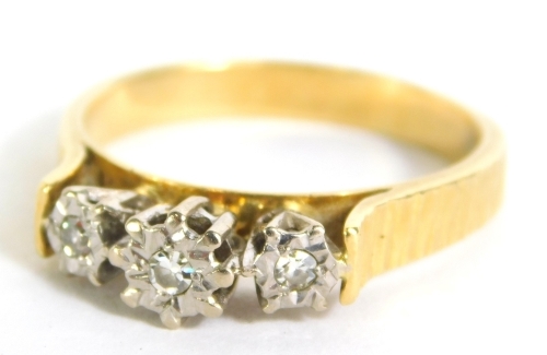 An 18ct gold and three stone diamond dress ring, on textured shank, size Q, 4.8g all in.