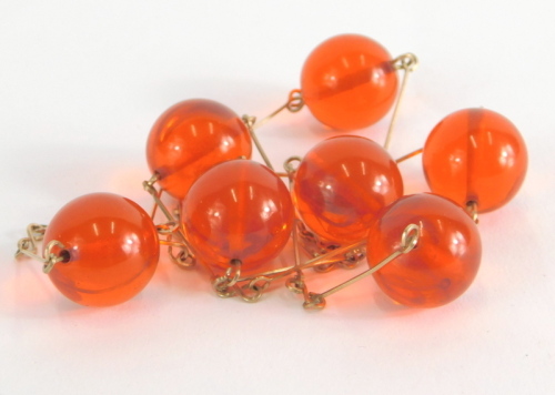 A cherry amber necklace, with seven beads, each approx 1.5cm long, on wire work plated frame, 58cm long overall, 29g all in.