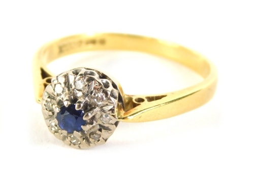 An 18ct gold dress ring, claw set with a central blue stone, surrounded by small diamonds, on a part pierced shank, size R, 4.1g all in.