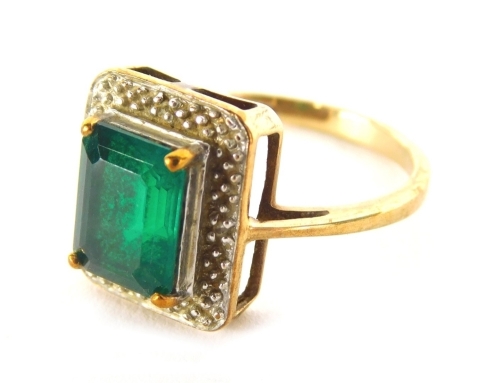 A 9ct gold Art Deco style dress ring, claw set with a central green stone on a textured part pierced shank, size N, 2.9g all in.