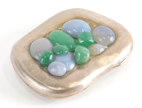 A polished pewter and applied pebble compact, shaped with green and clear stones, 8cm x 5cm.