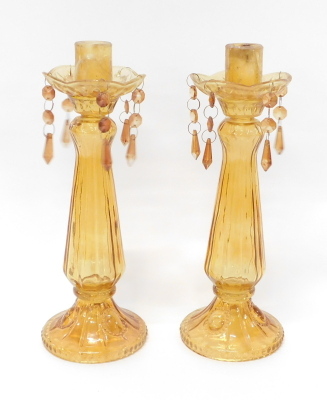 A pair of 20thC amber glass candlesticks, each on circular feet with cylindrical dish holders, 34cm high.