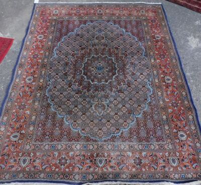 A Persian rug, with a central cartouche shaped medallion, in pale blue, on a navy blue ground, with one wide and two narrow border, 249cm x 195cm.