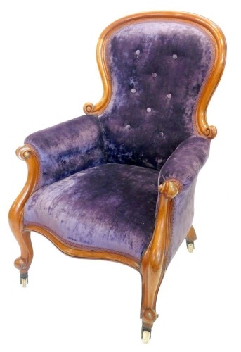 A Victorian mahogany show frame armchair, upholstered in buttoned purple velvet, on scroll carved supports with ceramic castors.