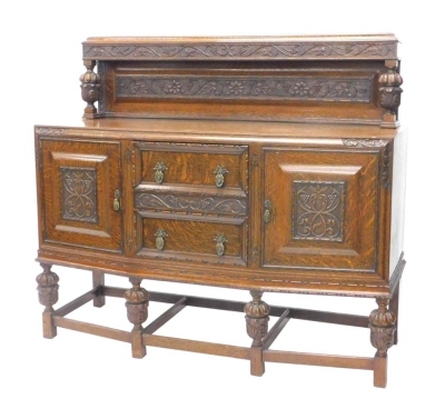 A 1920/30's oak sideboard, the raised back carved with grapes and vines, and with cup and cover supports, the bow fronted base with an arrangement of two drawers and two panelled doors, on matching supports, 154cm wide.