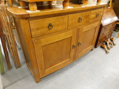 An oak bow front sideboard with drawers above two panelled doors, on stiles.