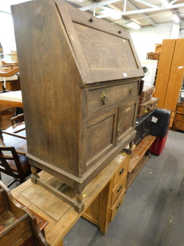 An oak bureau with a drawer and two panelled doors and an oak desk with a single pedestal etc. (AF)