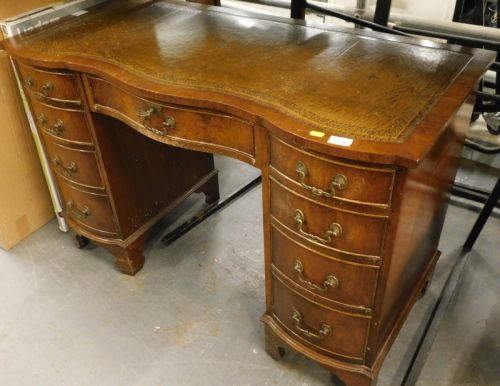A mahogany desk with brown leather insert and nine drawers on bracket feet.