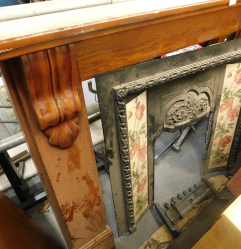 An oak fire surround with Victorian style cast iron inset with ceramic tiles printed with a design of poppies and leaves, etc.