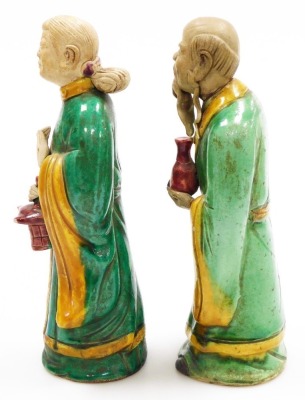 A pair of Chinese terracotta figures, in Tang dynasty style, each decorated in red, green and yellow, with a male and female figure holding a lantern and a vase respectively, 30cm and 29cm high. - 2