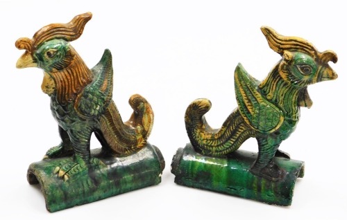 Two similar Chinese glazed pottery ridge tiles, in Ming dynasty style, each mounted with a mythical bird in yellow and mottle green glazes, 28cm high.