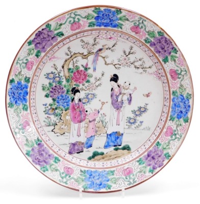 A Chinese porcelain charger, decorated with female figures, children, etc., within a floral border in delicate coloured enamels, 36cm diameter.