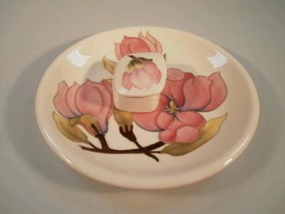 A Moorcroft plate with pink magnolia decoration on a cream ground