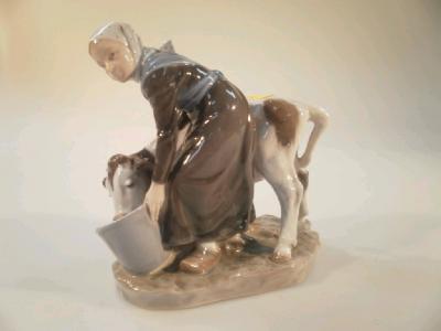 A Royal Copenhagen porcelain figure group of a Flemish cow girl with Friesian calf