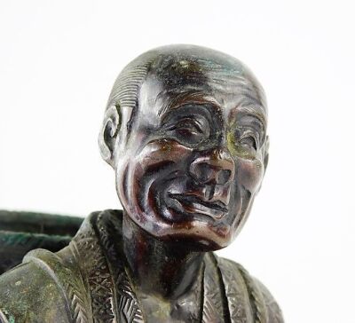 A Japanese bronze figure, Meiji period, modelled in the form of a man holding a gourd and a cup, whilst carrying a basket, unsigned, 17cm high. (AF) - 7