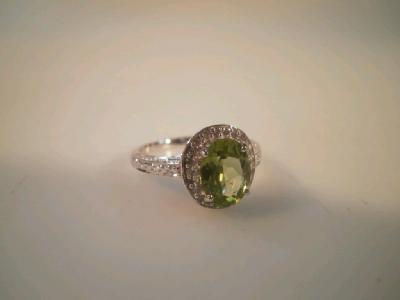 A dress ring set with a green stone (possibly peridot) surrounded by tiny