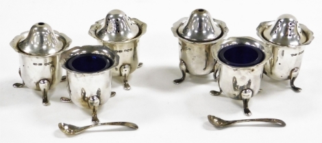 A George VI silver part cruet, comprising two salt pots, two pepper pots and two open salts with blue glass liners, each with a shaped border raised on three cabriole legs, with two spoons, Sheffield 1937, weighable silver 8½oz.