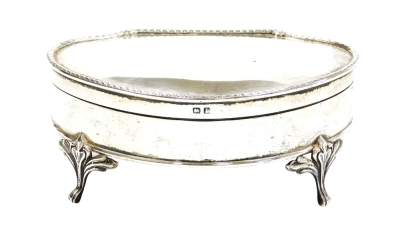 A George V silver jewellery casket, with patterned border, the hinged lid enclosing a green velvet fitted interior, raised on four scroll and heart shaped legs, Birmingham 1914, 14cm wide.