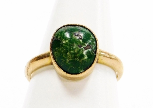 A dress ring, with polished green stone in a rub over setting, on a plain band, yellow metal, stamped 9ct, ring size P½, 3.4g all in. (AF)