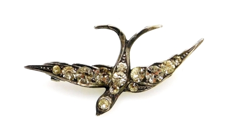 A swallow brooch, the out spanned wings set with paste stones, in a white metal casing on single pin, back unmarked, 4.5cm wide, 5.1g all in.