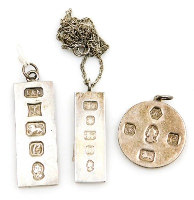 Three silver ingot pendants and a chain, comprising two standard vase Birmingham 1977 and Sheffield 1977, together with a circular ingot pendant Sheffield 1977 on a fancy link chain, white metal unmarked, 96.3g all in.