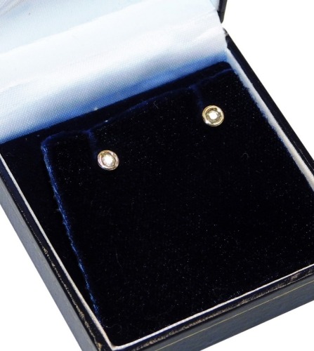 A pair of diamond stud earrings, each with round brilliant cut diamond, each approx 0.15ct, in a rub over white gold setting, on a yellow metal stick pin back marked 375, 1g all in, boxed.