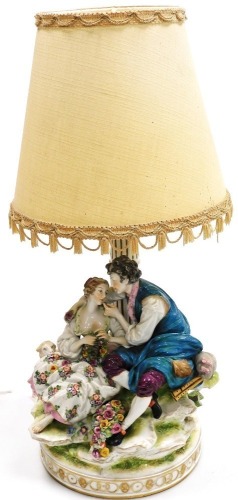 An early 20thC Continental porcelain figure group, modelled as a pair of lovers seated by a column, with a lamb and basket of flowers, now converted to a table lamp, 30cm high. (AF)