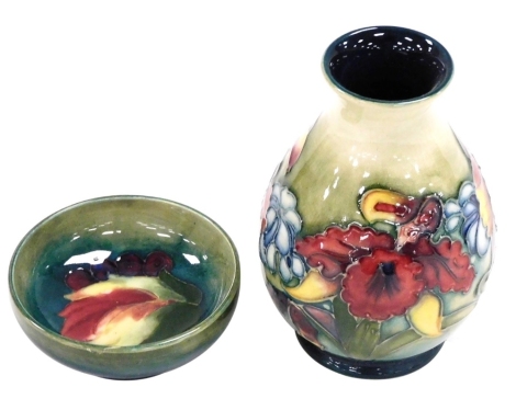 A Moorcroft pottery vase in the Orchid pattern, of baluster form, impressed marks, 12cm high, and a Moorcroft pottery Leaf And Berry pattern small dish, impressed marks, 7.5cm wide.