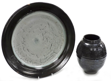 Two items of studio pottery, to include a charger with crackle blue glaze centre and black rim, 43cm diameter, and black glazed vase, 23cm high. (AF)