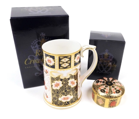 Two items of Royal Crown Derby porcelain, comprising a commemorative Millennium Imari tankard, in typical colourway and leaf cast handle, 13cm high, and an Old Imari pattern trinket box and cover, pattern MMVI, 8cm diameter, both boxed.