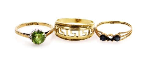 A gold and pale green gem stone set solitaire ring, possibly a peridot, size K, 9ct gold and sapphire three stone ring, one stone lacking, size L, and a yellow metal band with an open work Green key design, stamped K14, size N½, 4.7g all in. (3)