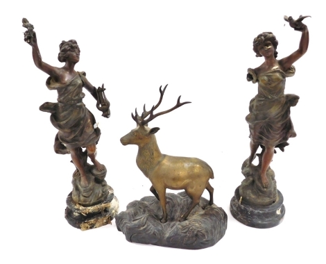 After Guillemain. A pair of spelter figures, 45cm high, together with a brass figure of a deer, raised on a naturalistic wooden base, 25cm wide (3, AF)