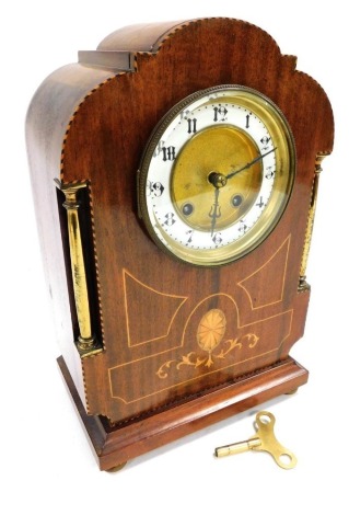 A late 19thC French mahogany cased mantel clock, circular brass dial with enamel chapter ring bearing Arabic numerals, BHA eight day Britannia movement, with coil strike, the case of arched fan form, with paterae and line inlay, and two brass columns, rai