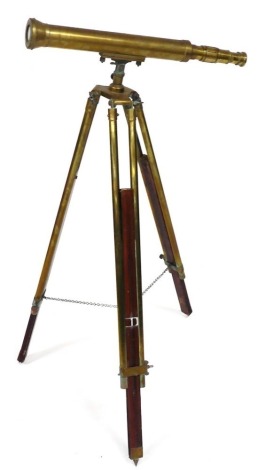 A brass telescope, on a brass and wooden tripod stand, 63cm wide.