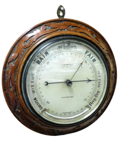 A Victorian circular oak cased barometer, by J Casartelli, 43 Market Street Manchester, with barometer, the case carved with scrolling leaves, 37cm diameter.