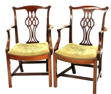 A pair of Chippendale style mahogany carver chairs, with scrolling crest rail, pierced and carved vase shaped splat, floral upholstered drop in seat, raised on square legs united by an H framed stretcher.