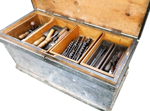 A carpenter's stained pine tool chest, containing moulding planes, saws, chisels, drill bits, set squares, etc., 99cm wide.