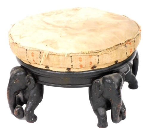 A late 19thC Anglo-Indian ebony circular footstool, raised on four carved elephant supports, 37cm wide.