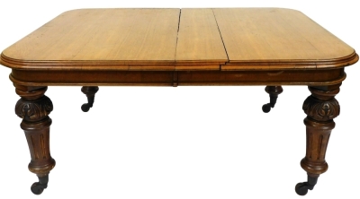 A Victorian oak wind out dining table, in two sections, raised on carved fluted and turned legs, brass capped on castors, 75cm high, 164cm wide, 135.5cm deep.