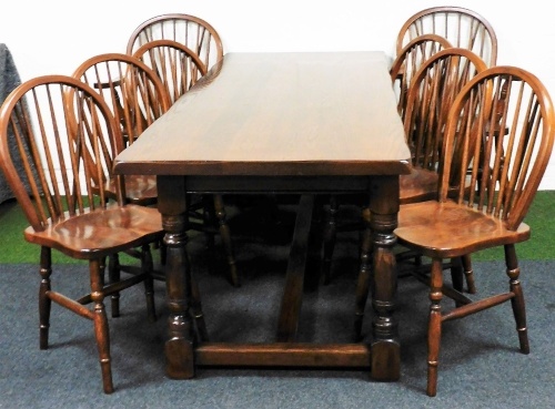 An oak refectory dining table, raised on turned legs, united by an H frame stretcher, 77cm high, 220cm wide, 84cm deep, together with a set of eight oak Windsor dining chairs, comprising a pair of carvers and six single chairs.